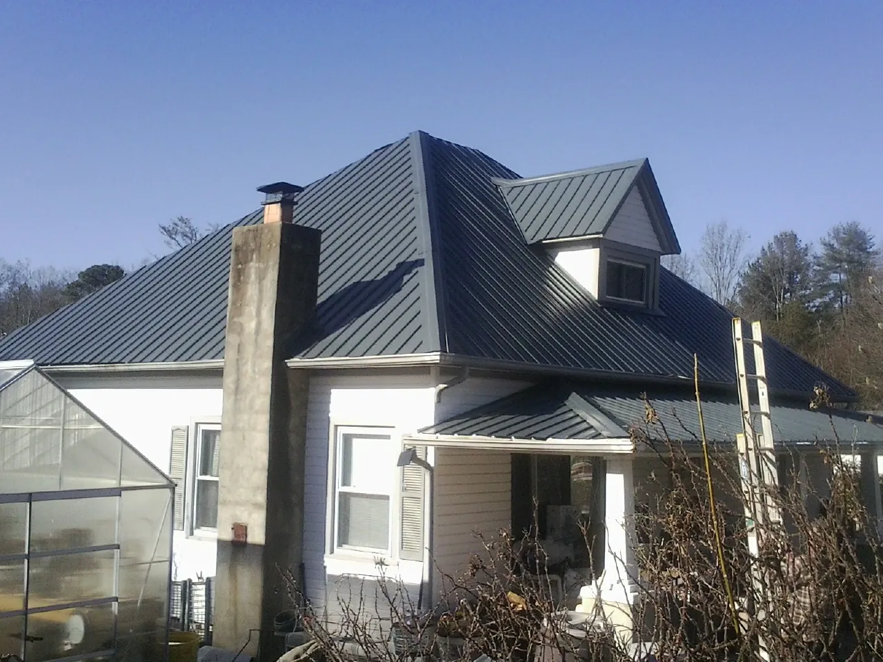 Dark blue standing seam metal roof on a white farmhouse with dormer — Slate & Tile Roof Repair by Roofing Brothers in Nevis