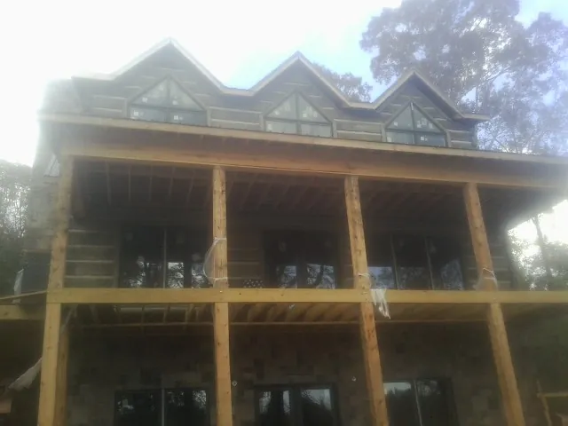 Dormers and porch framing on a large log home under construction — Roof Coating work by our crew in Nevis