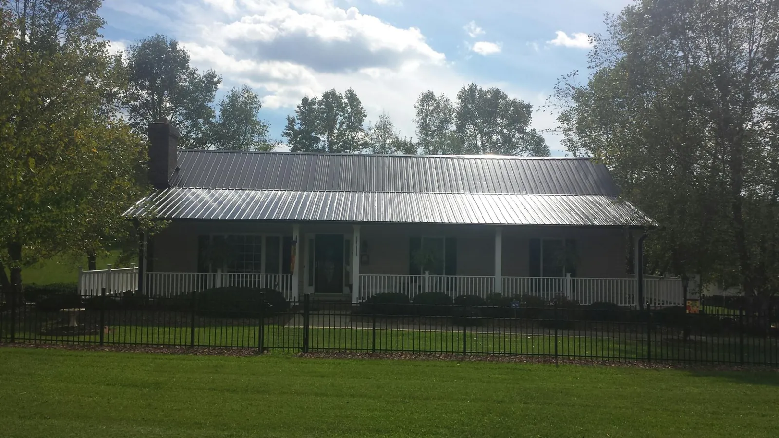 Gray metal roof on a brick ranch with a full width front porch — Gutter Guard Installation work by our crew in Nevis