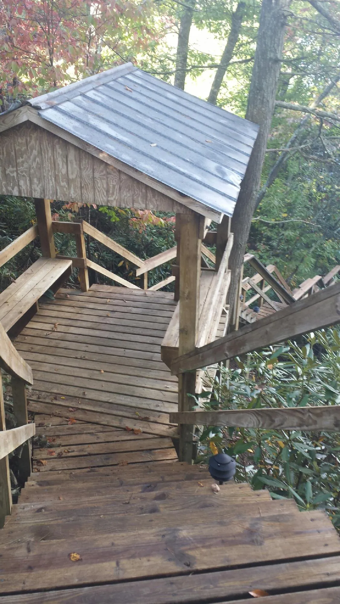 Metal roofed shelter over wooden steps on a wooded walkway — Skylight Repair & Installation work by our crew in Nevis